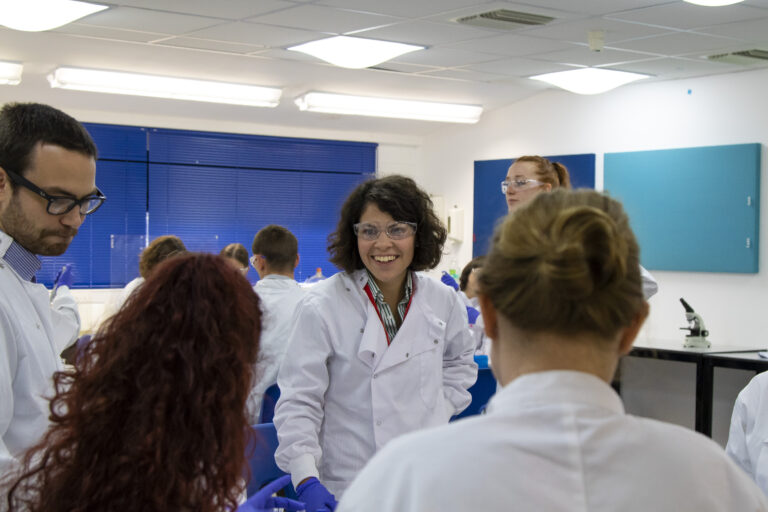 Teacher speaking with students of science and technology in a classroom